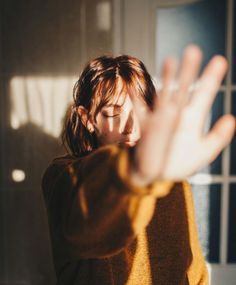 a woman is holding her hands up in the air while she stands near a window