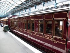 a maroon train is parked at the station