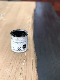 a can of black paint sitting on top of a wooden table next to a wall