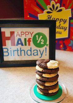 a stack of cookies sitting on top of a plate next to a happy birthday sign