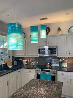 a kitchen with marble counter tops and blue lights hanging from the ceiling over the stove