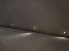 some lights are on in the corner of a room with concrete walls and flooring