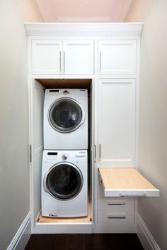 a white washer and dryer in a small room with built - in cabinets