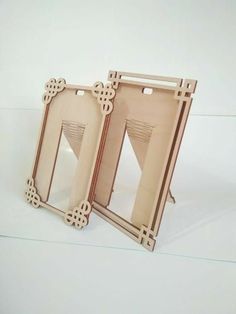 two wooden frames sitting next to each other on a white surface with one open and the other closed