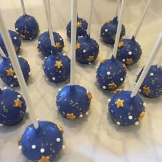 blue cake pops with gold stars and white sprinkles are arranged on a table