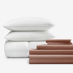 four pillows stacked on top of each other in front of white sheets and brown pillow cases