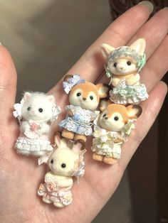 a person's hand holding five tiny animal figurines