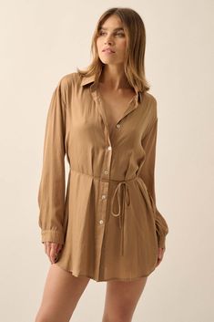 Matte-finish satin romper. Layered design with dress shirt overlayer and shorts lining. Collared neckline. Button-front closure with pearly shell buttons. Long sleeves with buttoned cuffs. Drop shoulder. Removable tie belt. Side slits. Yoke back. Curved shirttail hem. Thigh length. Relaxed fit. 100% Polyester. Imported. Designed in LA. Model wears size S. Classic Summer Mini Dress With Button Closure, Classic Mini Dress With Button Closure For Summer, Elegant Rayon Mini Dress For Daywear, Chic Rayon Shirt Dress For Daywear, Formal Summer Button-up Shirt Dress, Elegant Rayon Shirt Dress For Summer, Elegant Button-up Mini Dress For Brunch, Elegant Shirt Dress With Button Cuffs And Shirttail Hem, Chic Daywear Shirt Dress With Covered Buttons