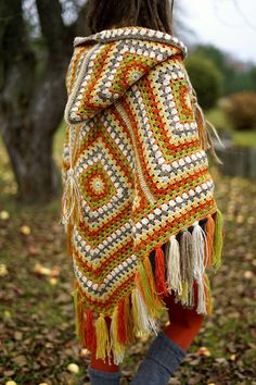 a woman is wearing a crocheted shawl in the fall with leaves on the ground