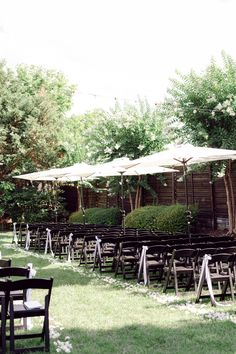 rows of chairs and umbrellas set up for an outdoor wedding ceremony in the grass