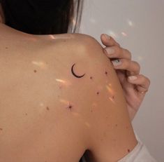 the back of a woman's shoulder with stars and a crescent tattoo on it