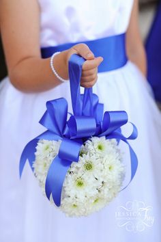 a person in a white dress holding a blue and white bouquet with flowers on it