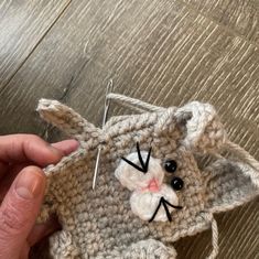 someone is holding up a crocheted cat ornament to show it's face