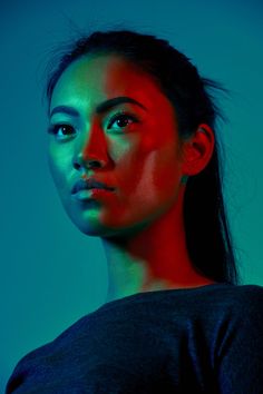 a woman is posing for the camera with red and blue lighting on her face,