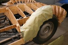 a car is being built with wood and plastic wrap around the wheel rims on it