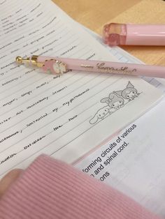 a pink pen sitting on top of a piece of paper next to an open notebook