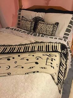 a bed with black and white comforter on it in a pink walled room next to a wooden headboard