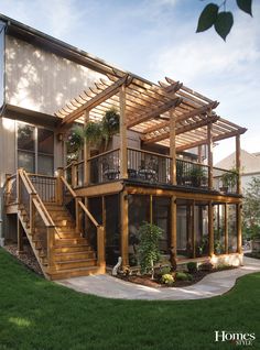 a large house with wooden stairs and plants on the balconies, surrounded by green grass