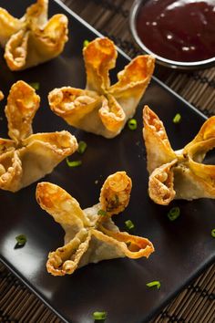 small appetizers on a black plate with dipping sauce