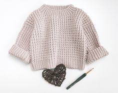 a knitted sweater and crochet heart next to a knitting needle