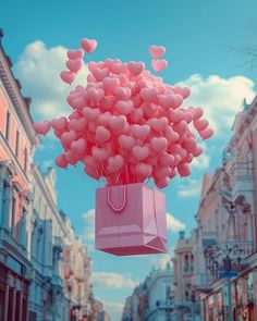 a pink bag filled with heart shaped balloons floating in the air over a city street