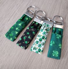 four pairs of green and black tie with shamrocks on them hanging from metal hooks