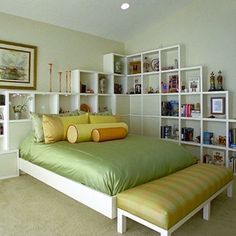 a bed sitting in the middle of a bedroom next to a book shelf filled with books