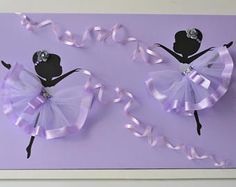 a paper cutout of two ballerinas with ribbons