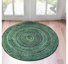 a green rug is on the floor in front of a door with two windows and wooden floors