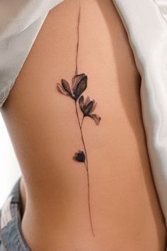 the back of a woman's stomach with a flower tattoo on it