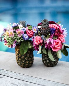 two pineapple vases filled with colorful flowers next to a pool