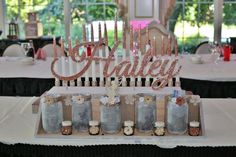 a table topped with lots of bottles filled with liquid next to a sign that says happily