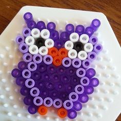 an owl made out of plastic beads on a white plate