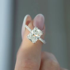 a woman's hand holding a diamond ring