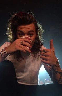 a man with long hair drinking from a cup