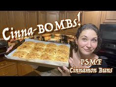 a woman holding up a pan of food in her kitchen with the caption, cinnamon buns