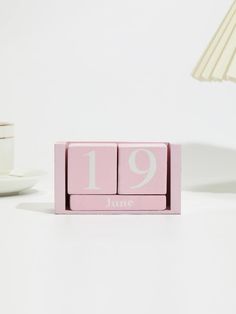 a pink wooden block with the number 19 on it and a white lamp next to it