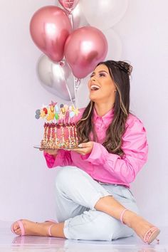 a woman sitting on the floor with a cake and balloons