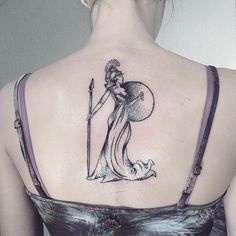 the back of a woman's shoulder with a lady holding a staff tattoo on it