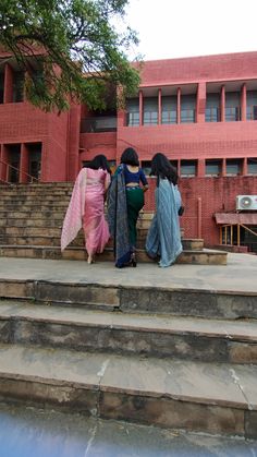 three women walking up some steps in front of a building