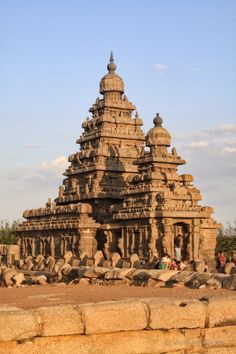 a large stone structure with statues on the sides and people standing in front of it