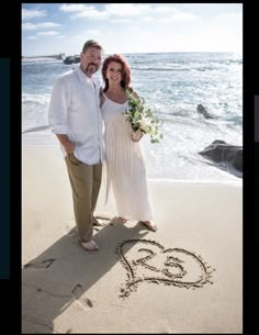 a man and woman are standing on the beach in front of an i love you written in the sand