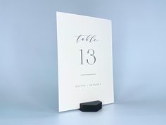 a white table number card with the date 13 on it and a black square stand