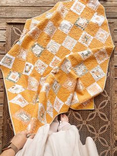 someone is laying down on the floor with their feet propped up next to a yellow and white quilt