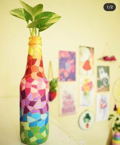 a bottle with a plant in it sitting on a table next to pictures and plants