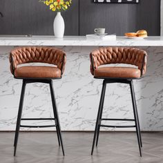 two brown leather barstools in front of a marble countertop with flowers on it