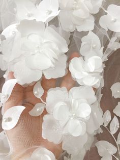 a close up of a person's hand with white flowers on it