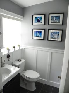 a white toilet sitting in a bathroom next to a sink and a bath room with pictures on the wall