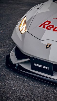 the front end of a white sports car with red lettering on it's hood