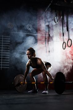 a woman squatting with a barbell in her hands - stock photo - images